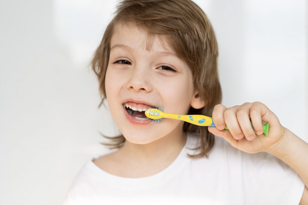 A little boy brushes his teeth with a toothbrush, care for coil teeth, oral hygiene,happy face