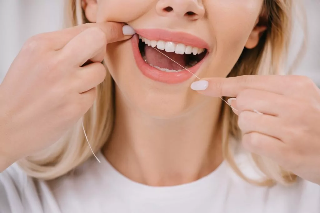 woman flossing teeth with dental floss