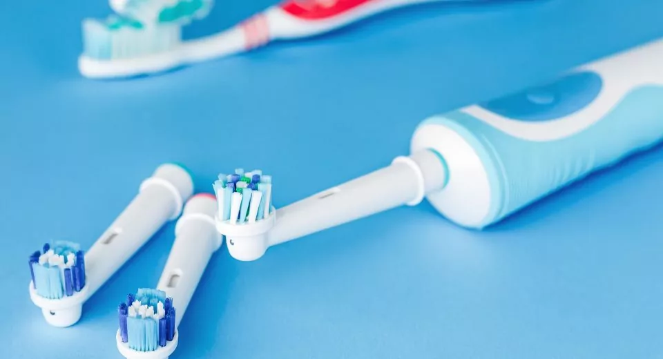 Electric and manual toothbrush on blue background
