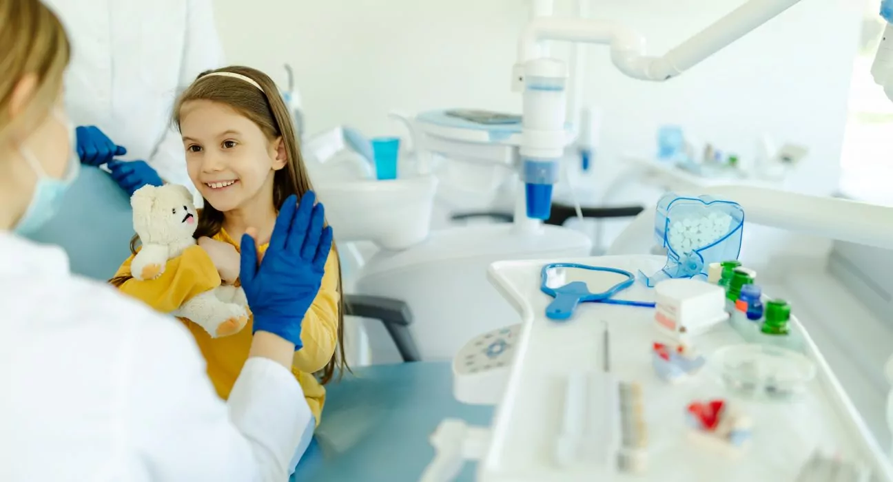 Female doctor is giving hi five to little girl after a successful dental examination.