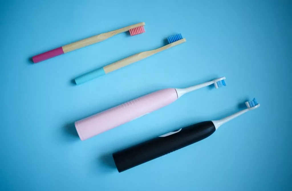 ultrasonic electric and bamboo toothbrushes on a blue background