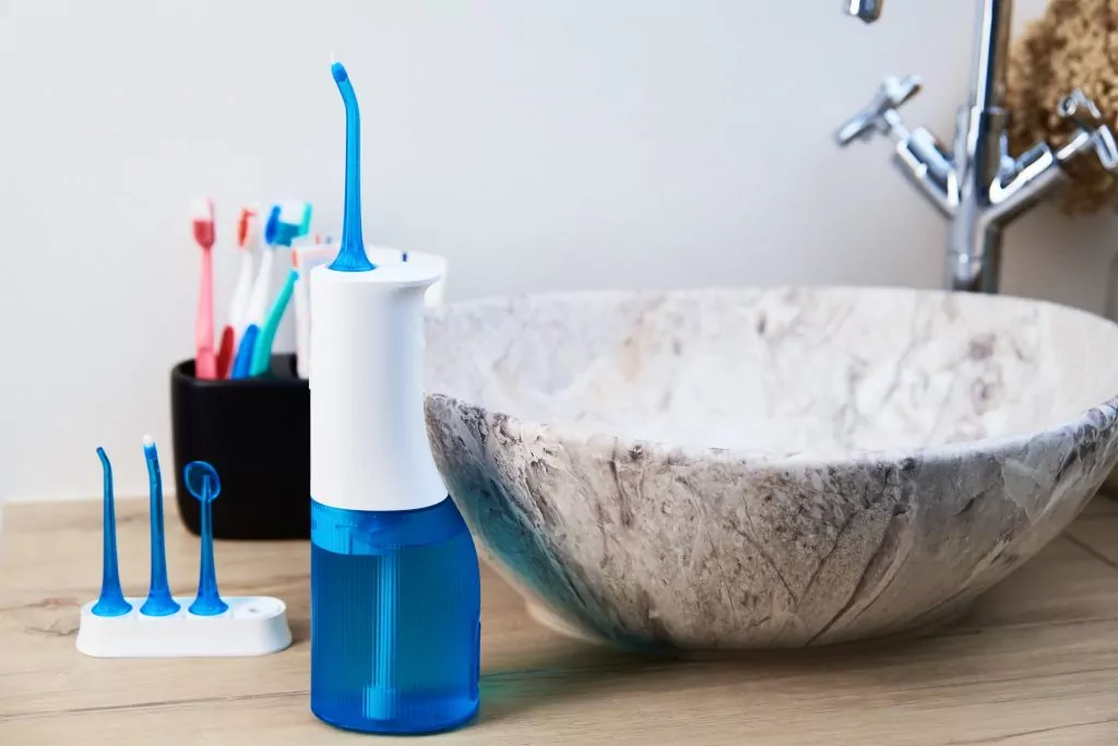 Portable oral irrigator kit in bathroom, waterpik for family use