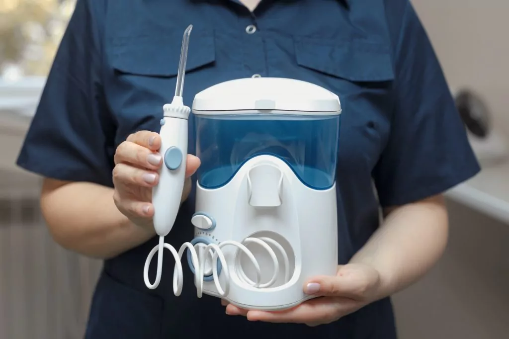 The dentist holds in hands a water oral irrigator for cleaning and hygiene of the dental cavity