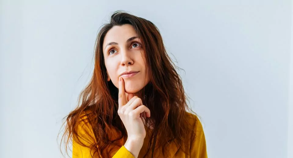 worried woman with her finger in her mouth and her hair ruffled and dirty.